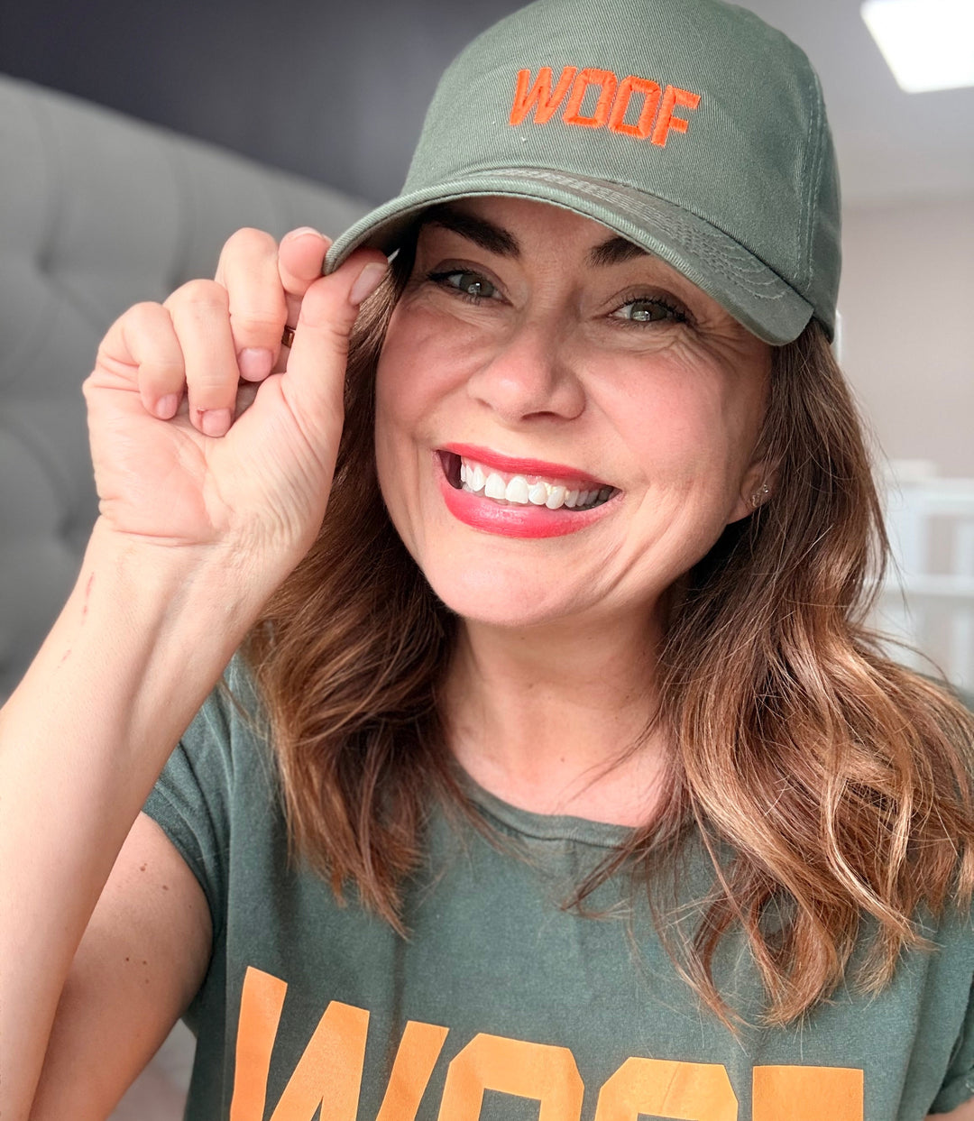 Woman wearing a green cap and t-shirt with 'WOOF' text, indoors.