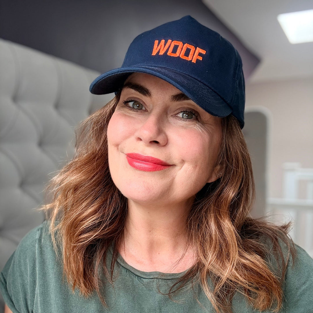 Person wearing a navy cap and green t-shirt with 'WOOF' text indoors.