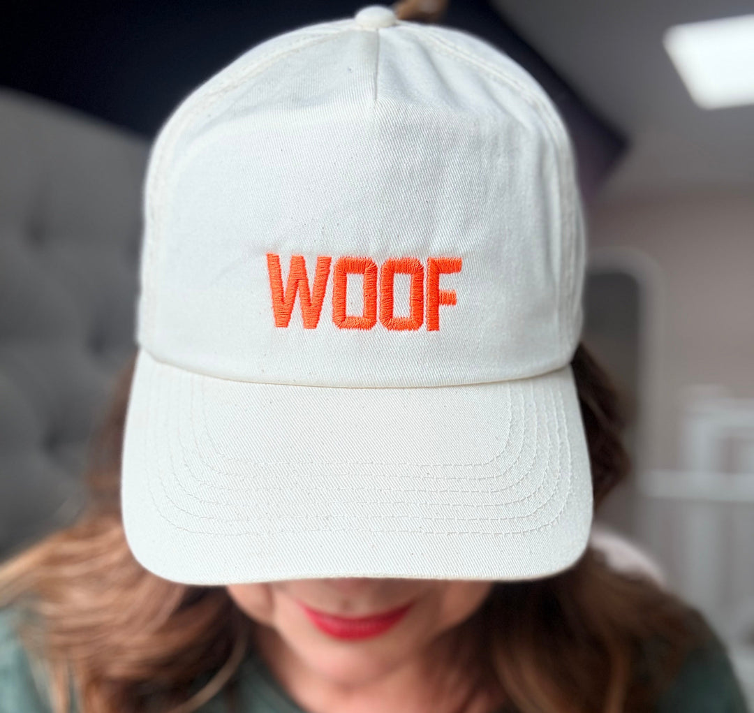Person wearing a white cap with 'WOOF' in red text, blurred background