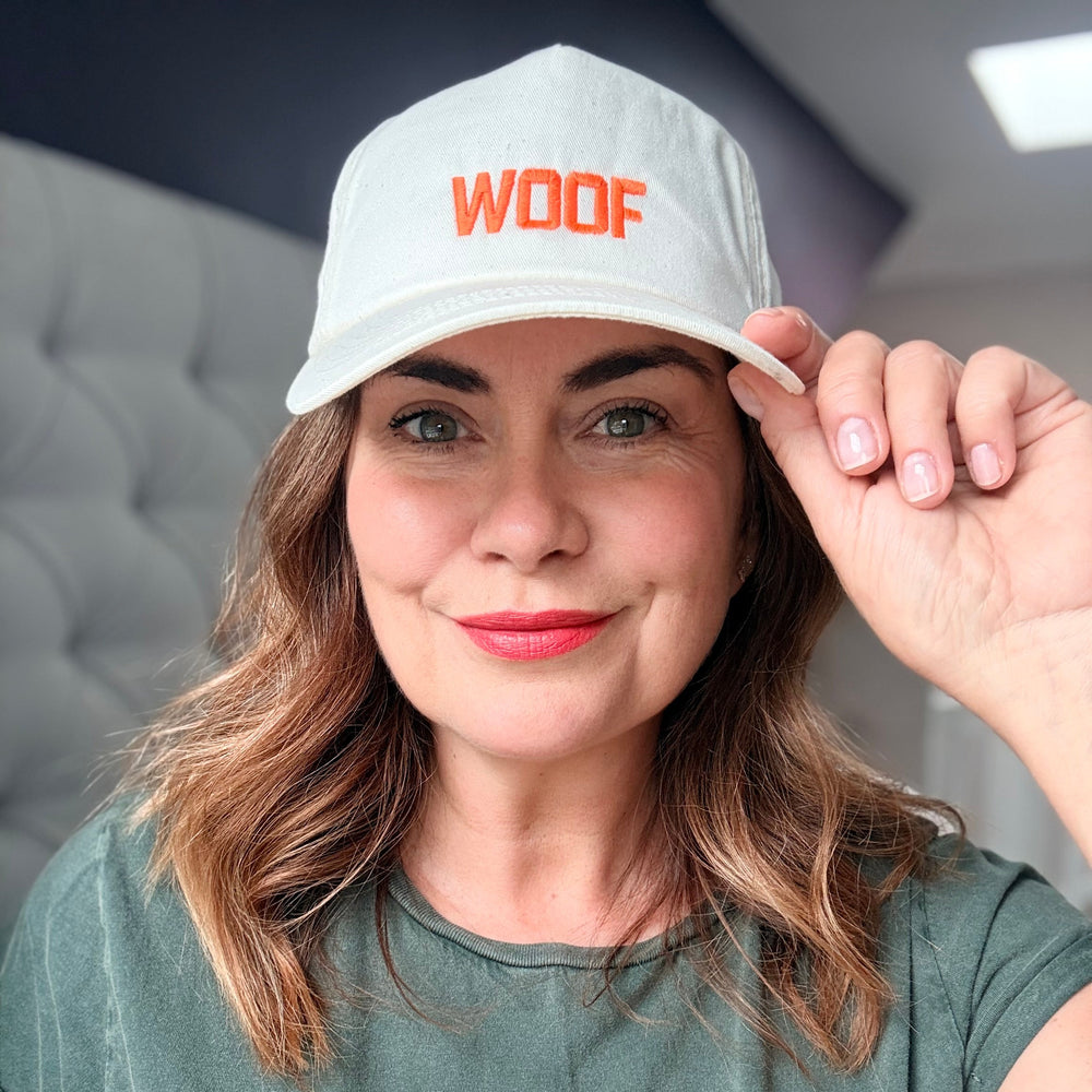 Person wearing a white cap and green t-shirt with 'WOOF' printed on them, indoors.
